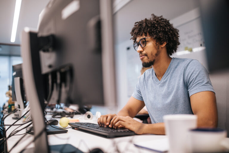 Young black programmer meeting regulation software upgrade compliance by upgrading software on a PC in the office.