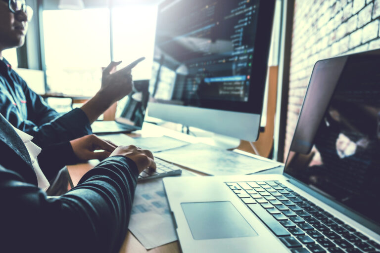 Team of IT professionals working with computers and programs to manage their organization's defense against cybercriminals.