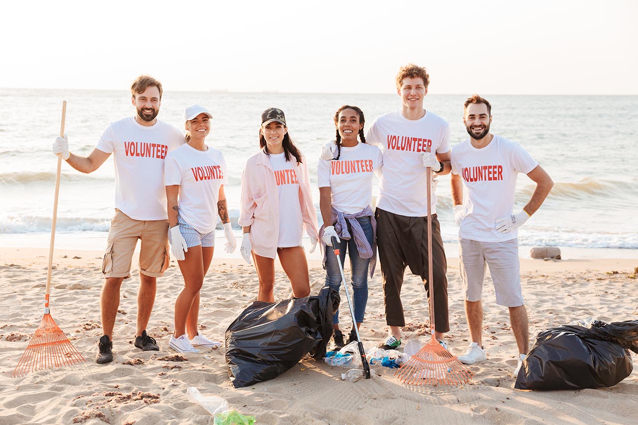 Image of happy multinational voluntary workers cleaning beach fr volunteers for a jacksonville nonprofit
