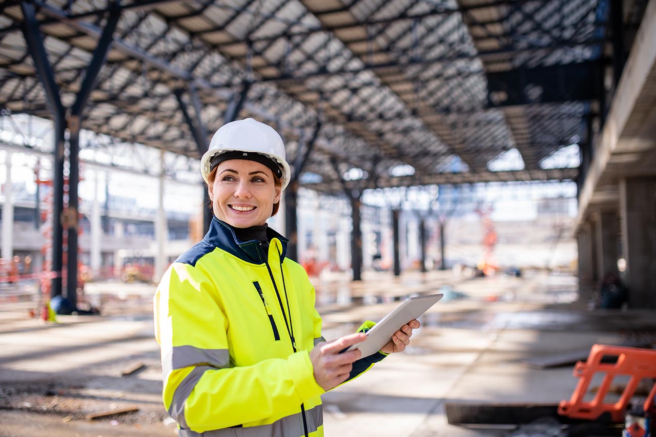 A woman engineer with tablet standing on construction site, working. contruction worker with mobile device