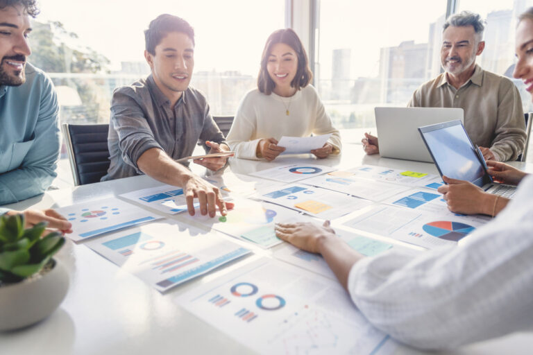 FTC Safeguards Rule compliance concept - Business people pointing to different documents with financial figures on a table.