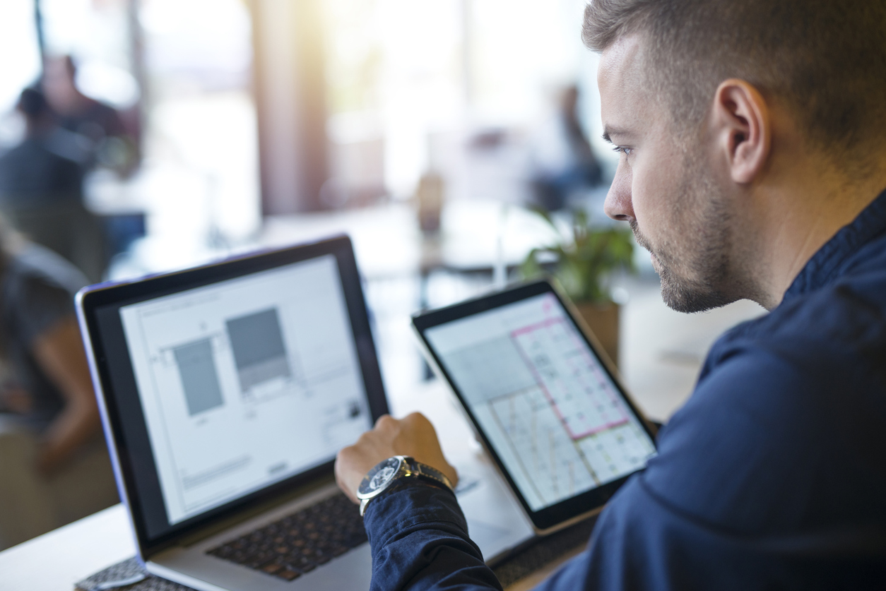 Procurement in IT lifecycle management - Businessman using a laptop and tablet device to check the latest technology for his company.