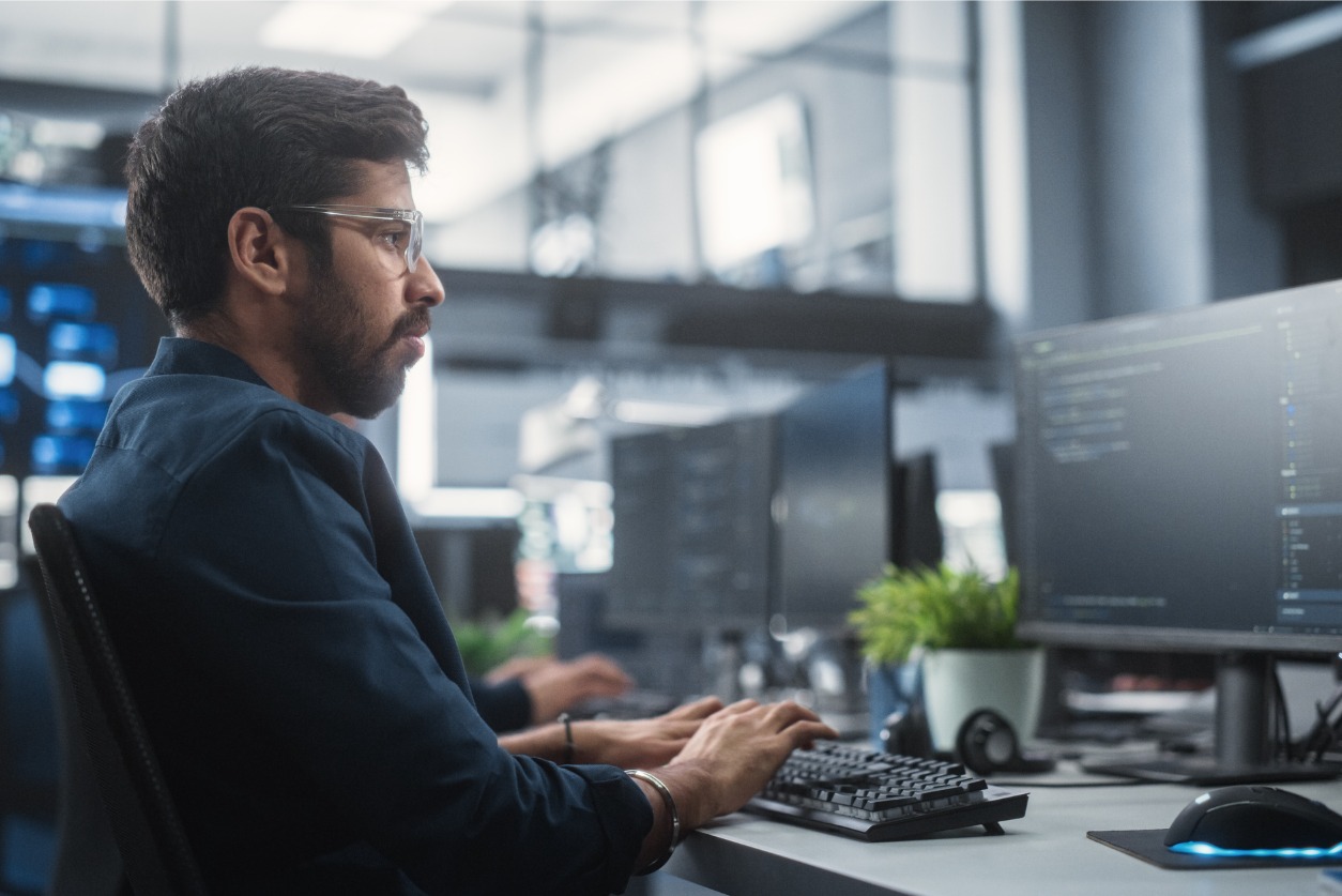 IT lifecycle management - Male IT expert using multiple computers to monitor overall functioning of company hardware.