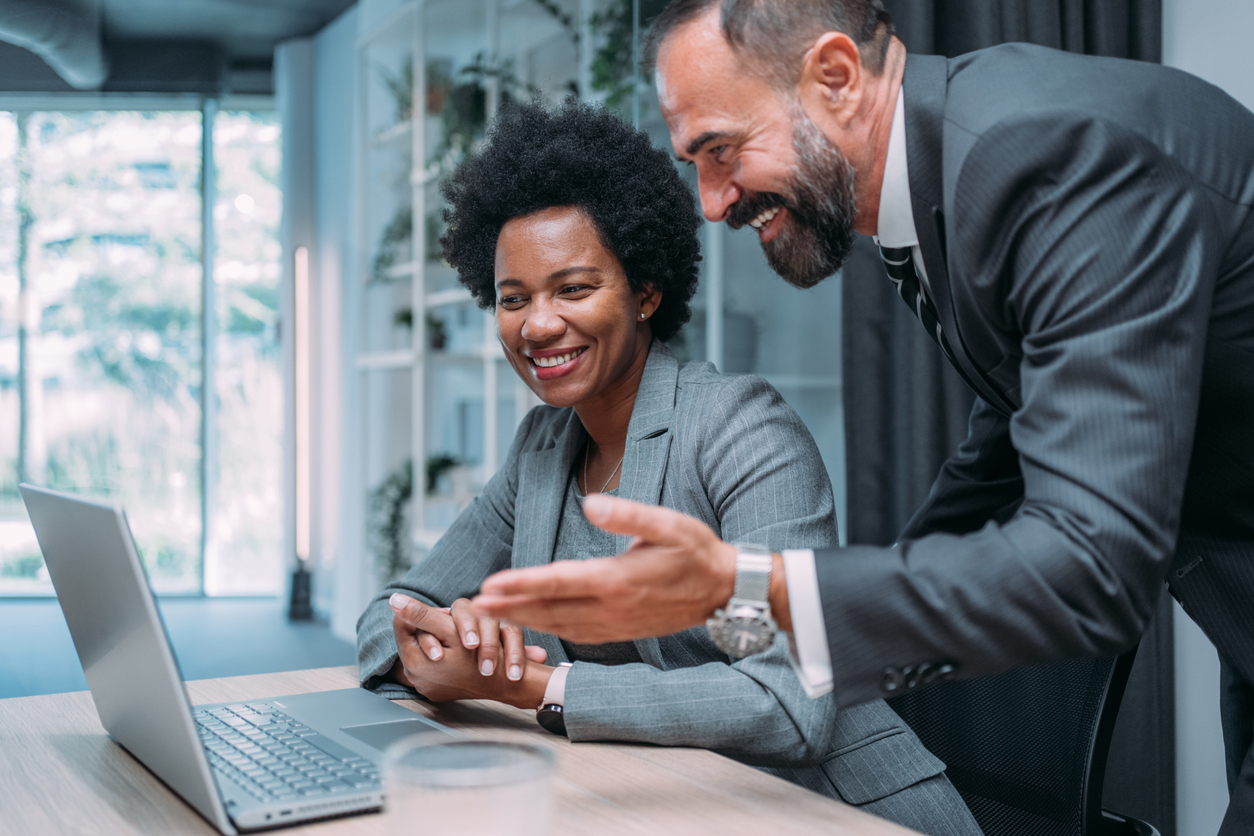 Male boss with female employee working on a laptop computer to deal with common it helpdesk issues