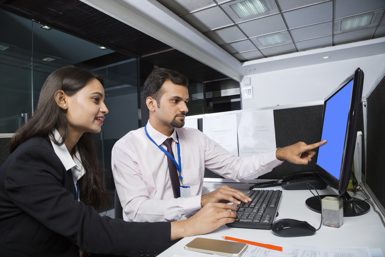 male and female employee looking at computer monitor with blue screen