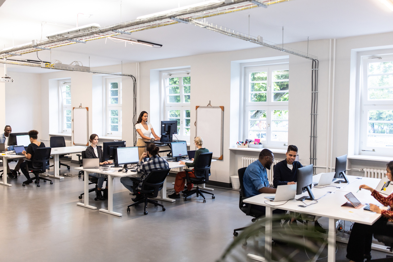 A group of employees in an office accessing files in computers by using a shared network drive.