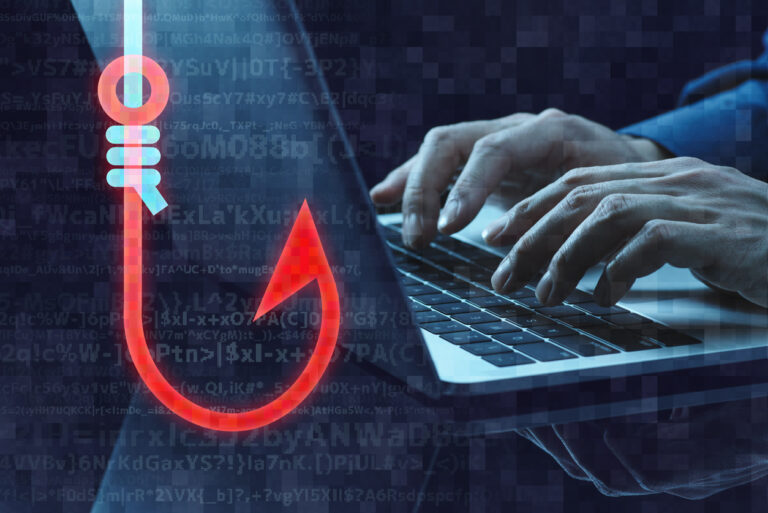 Phishing scam concept- A male hacker using a laptop to use phishing scams that target businesses.