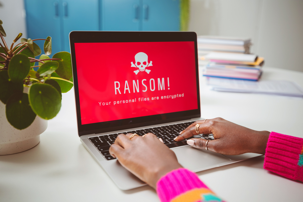 Phishing attack on business data - A woman using a laptop showing a ransomware attack.