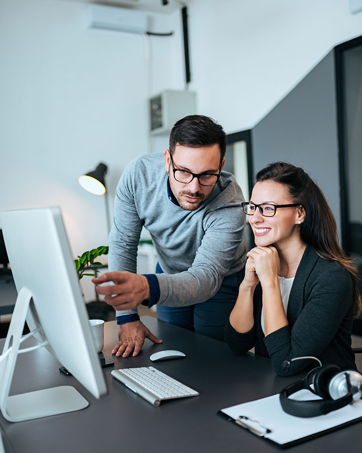 Two confident young business people looking at computer monitor. office workers with productivity due to co managed it