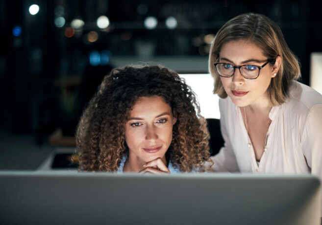 Professionals looking at a computer while working in an office to suggest managed IT services cost.