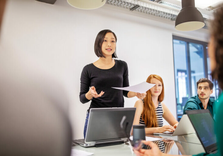 Confident female professional discussing in board room. Group of business colleagues planning together in meeting.