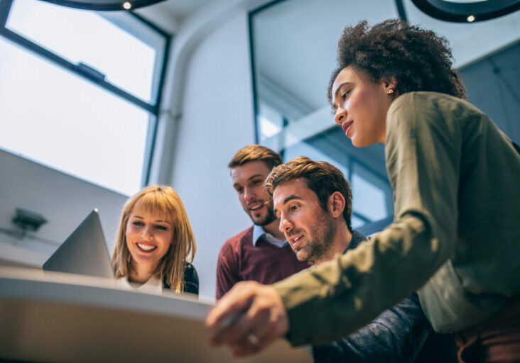 Team of business professionals in an office using a laptop device to check on Office 365 outsourcing features.